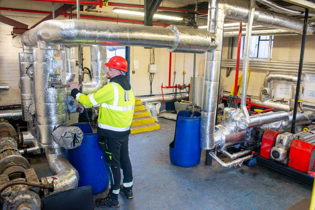 The pumphouse at tennants bitumen in Belfast with an employee checking the valve