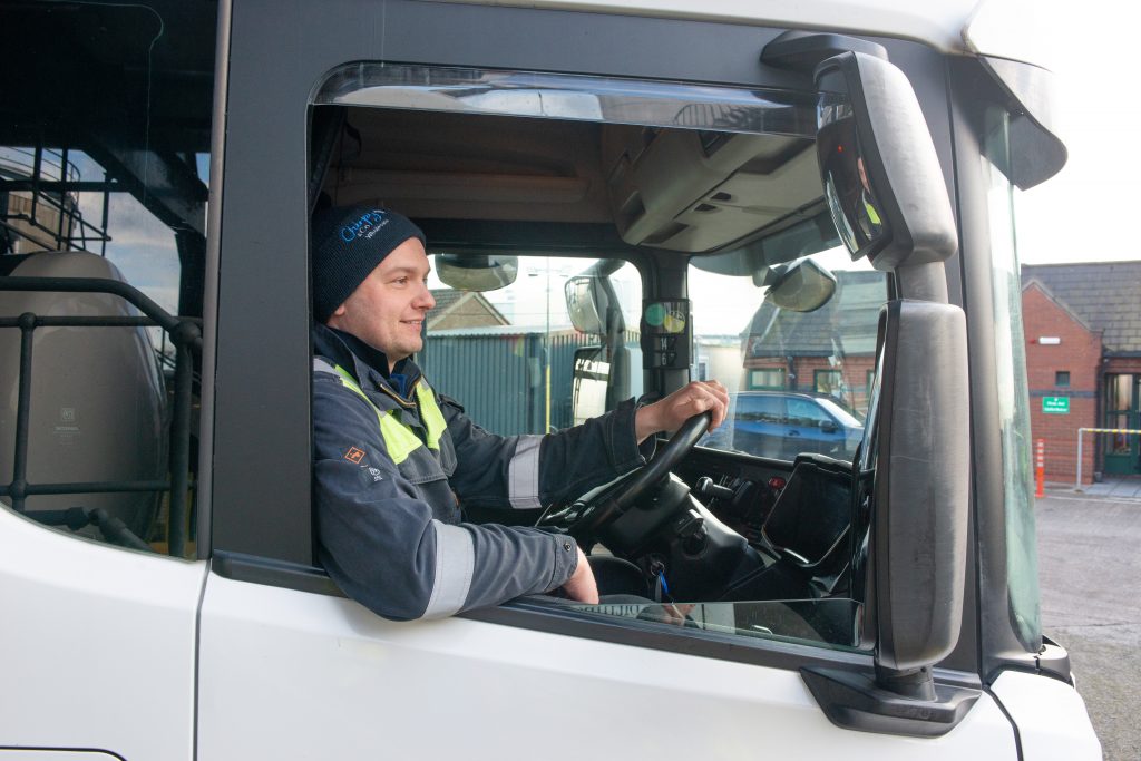Lorry driver in the cab driving off after filling the lorry with Tennants Bitumen