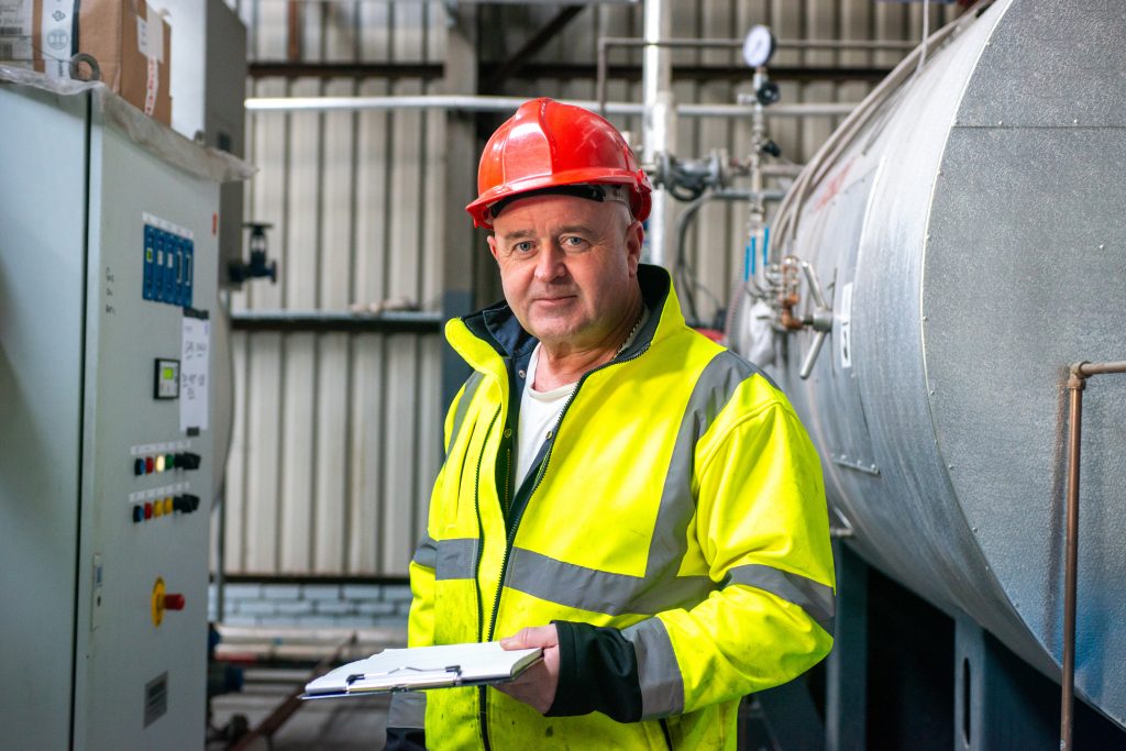 An employee at Tennants Bitumen with a clipboard in the boilerhouse