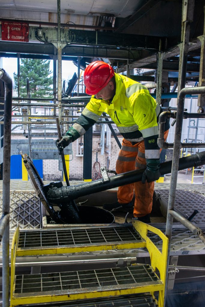 Driver placing the pipe into the lorry tank to get filled with Tennants Bitumen