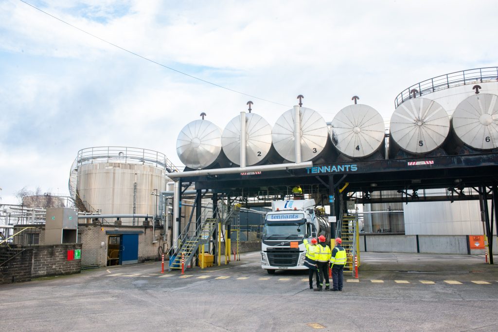 three employees at Tennants Bitumen inspecting the overhead tanks from the ground while a lorry is being filled.